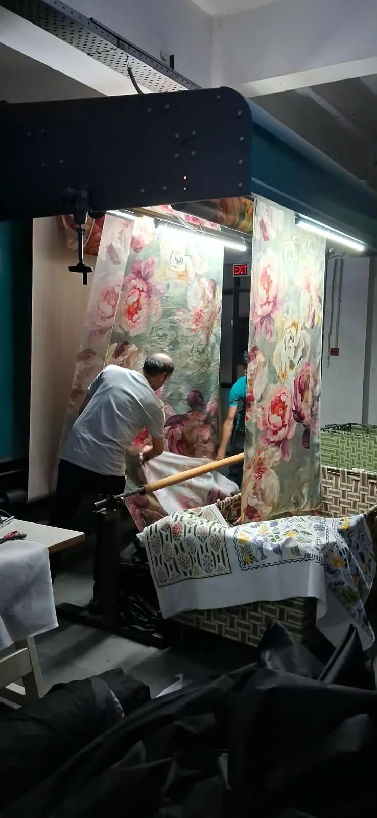 Workers rolling digitally printed peony fabric off the inspection frame