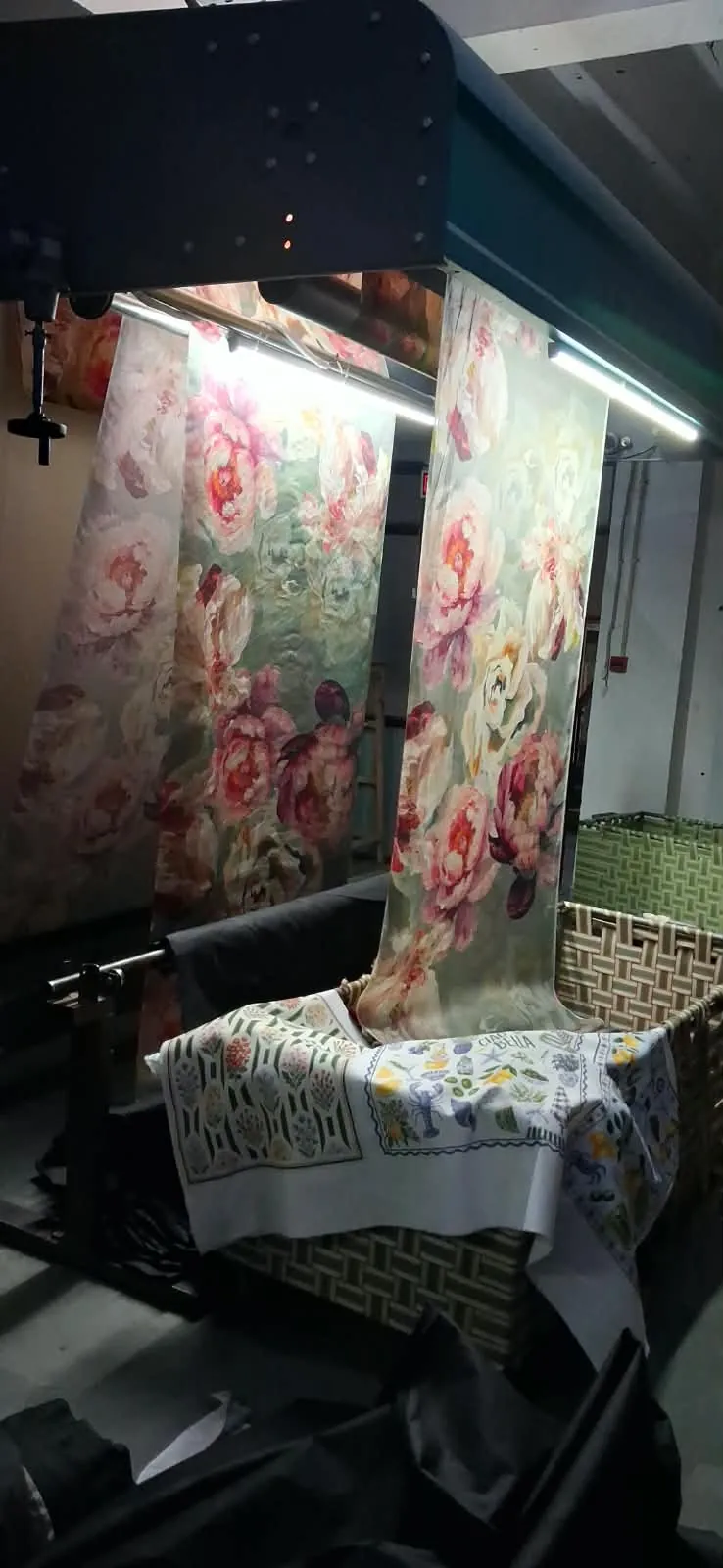Lengths of digitally printed fabric with large painterly pink peonies hanging on Fabloom's lit inspection frame